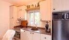 Helle Küche mit Granitarbeitsplatte, Einbaugeräten, Fenster und Dekoration in der Ferienwohnung Cala Murada