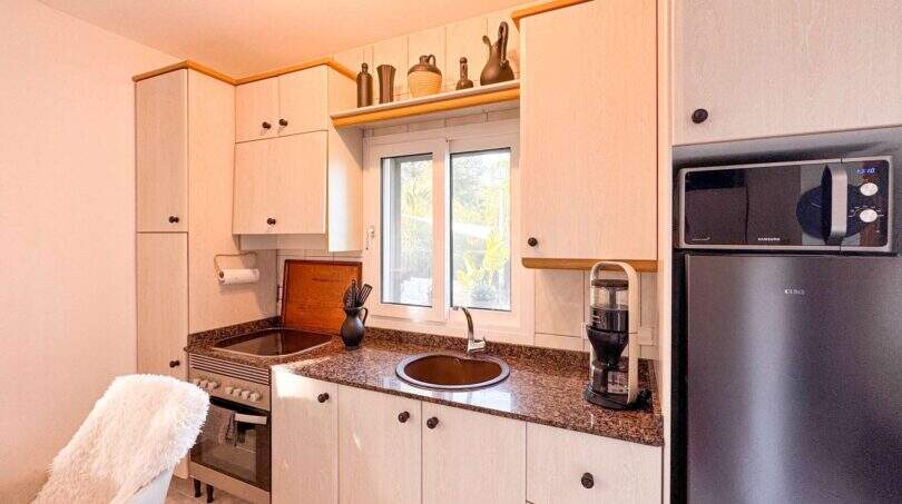 Helle Küche mit Granitarbeitsplatte, Einbaugeräten, Fenster und Dekoration in der Ferienwohnung Cala Murada
