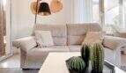 Helles Wohnzimmer mit grauem Sofa, Kaktus-Deko und großen Fenstern in Strandwohnung Cala Murada