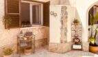Mediterraner Außenbereich mit Natursteinwand, Holzfensterläden und dekorativen Regalen in Cala Murada