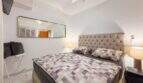 Helles Schlafzimmer mit Doppelbett, gepolstertem Kopfteil, Wandspiegel und Klimaanlage in Cala Murada