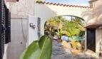 Überdachter Durchgang mit Rundbogen, tropischen Pflanzen und Blick auf den Pool der Ferienvilla in Cala Murada