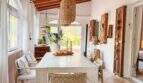 Heller Essbereich mit Holzbalkendecke, Rattanlampe, weißem Tisch und Orangendeko in Strandvilla Cala Murada