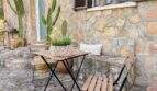 Rustikale Terrasse mit Bistrotisch, Kaktus und Sommerdekor an Natursteinmauer in Cala Murada