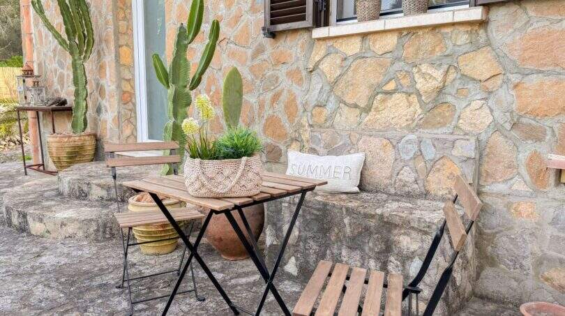 Rustikale Terrasse mit Bistrotisch, Kaktus und Sommerdekor an Natursteinmauer in Cala Murada