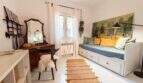 Helles Schlafzimmer mit antikem Schminktisch, weißem Tagesbett, Gemälde und Naturrugs in Cala Murada