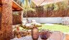 Sonnige Terrasse mit Lounge-Bereich, Sonnensegel, Natursteinwand und gepflegtem Rasen nahe Cala Murada