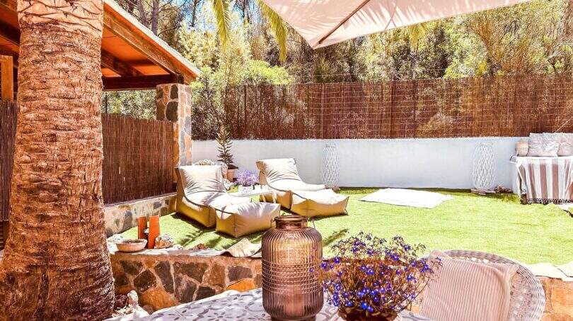 Sonnige Terrasse mit Lounge-Bereich, Sonnensegel, Natursteinwand und gepflegtem Rasen nahe Cala Murada