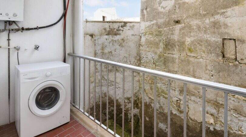 Balkon mit Waschmaschine und Warmwasserboiler, umgeben von Natursteinmauern in Felanitx
