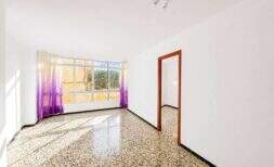 Sala de estar vacía con piso de terrazo, cortinas púrpuras y gran ventana en Felanitx
