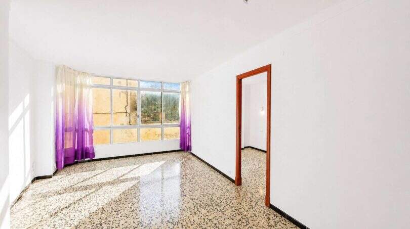 Leeres Wohnzimmer mit Terrazzoboden, lila Vorhängen und großem Fenster in Felanitx