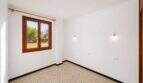 Leeres Schlafzimmer mit Terrazzoboden, Holzfenster und Gartenblick in einem Wohnhaus in Felanitx