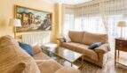 Helles Wohnzimmer in Felanitx mit zwei Sofas, Glastisch, Gemälde und großem Fenster mit Spitzengardinen.