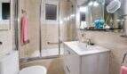 Modernes Badezimmer mit Glasdusche, weißem Waschtisch und Spiegelbeleuchtung in Felanitx