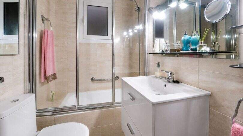 Modernes Badezimmer mit Glasdusche, weißem Waschtisch und Spiegelbeleuchtung in Felanitx