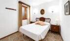 Schlafzimmer mit Doppelbett, Holzkopfteil, gemustertem Fliesenboden und Fenster mit Holzrahmen in Felanitx