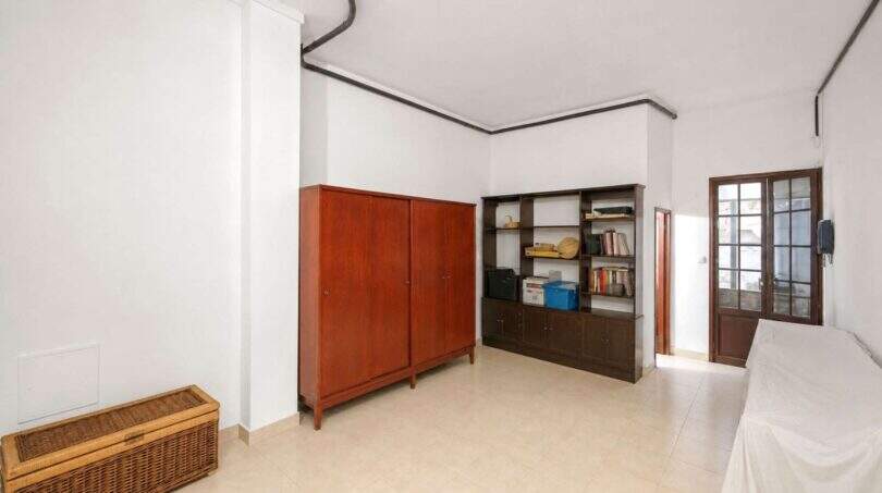 Helles Zimmer in Felanitx mit Holzschrank, Bücherregal, Terrassentür und Fliesenboden