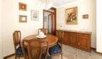 Klassisches Esszimmer mit rundem Holztisch, Rattanstühlen, Kristalllüster und antikem Sideboard in Felanitx