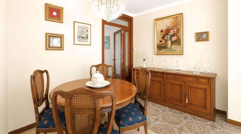 Klassisches Esszimmer mit rundem Holztisch, Rattanstühlen, Kristalllüster und antikem Sideboard in Felanitx