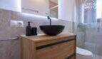 Modernes Bad mit schwarzem Aufsatzwaschbecken, Holzwaschtisch, Glasdusche und WC im Bungalow Alcúdia.