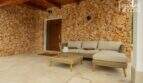 Überdachte Terrasse mit Natursteinwand, Lounge-Sofa und Holzdecke – Bungalow in Alcúdia