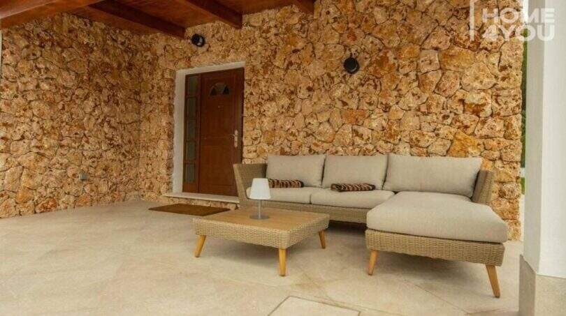 Überdachte Terrasse mit Natursteinwand, Lounge-Sofa und Holzdecke – Bungalow in Alcúdia