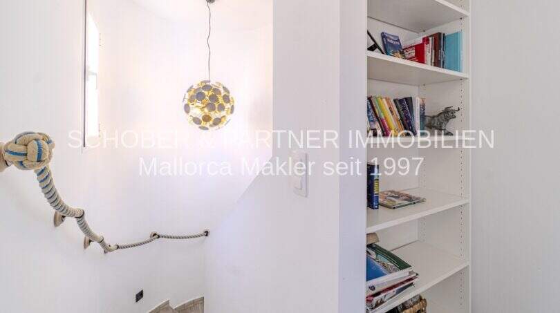 Treppenaufgang mit Seilgeländer, Designerlampe und weißem Bücherregal in mediterraner Villa Sa Coma