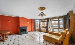 Amplia sala de estar con chimenea, paredes de color naranja, piso de baldosas y grandes ventanas en Felanitx
