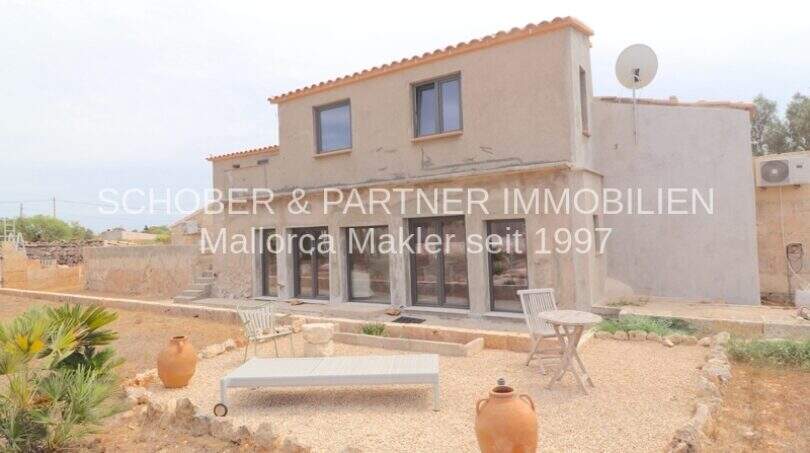 Außenansicht eines sanierten Landhauses in Portocristo mit Terrasse, Kiesgarten und mediterranen Tonamphoren.