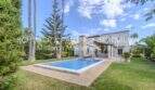 Mediterrane Villa in Sa Coma mit pool, gepflegtem Garten und Palmen unter blauem Himmel.