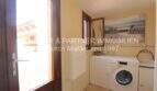 Utility room with washing machine, small window and wall picture in Villa Son Servera