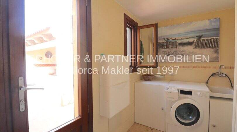 Utility room with washing machine, small window and wall picture in Villa Son Servera
