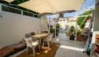 Terraza cubierta con mesa de comedor, área lounge y vista a piscina y jardín de una casa multifamiliar en Felanitx.