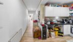 Pasillo estrecho con piso de madera y cocina blanca con encimera oscura en casa multifamiliar alquilable, Felanitx
