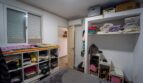 Vestidor con estantes abiertos llenos de ropa, aire acondicionado y ventana en casa unifamiliar en Felanitx.