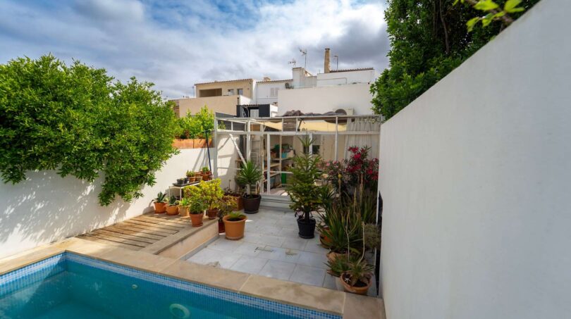 Patio interior con piscina, plantas de terraza e invernadero cubierto de una casa multifamiliar en Felanitx
