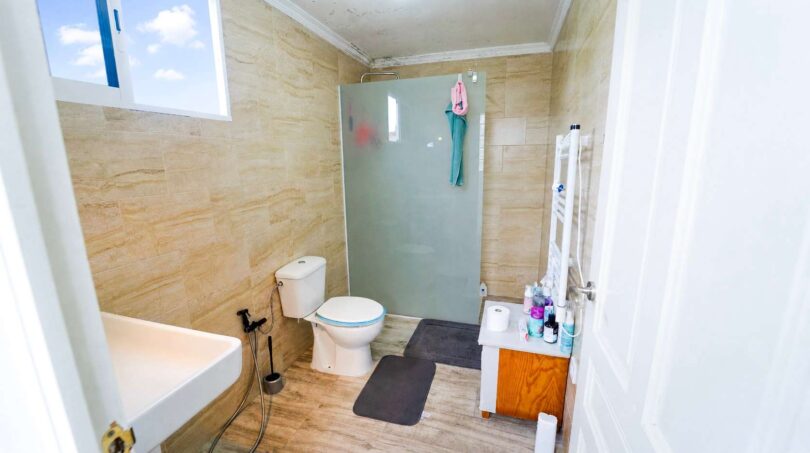 Baño con cabina de ducha, inodoro, bañera y suelo de madera en casa unifamiliar alquilada en Felanitx