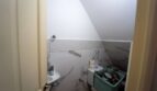 Pequeño aseo bajo techo inclinado con azulejos de mármol, lavabo y almacenamiento en casa unifamiliar Felanitx