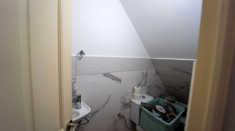 Pequeño aseo bajo techo inclinado con azulejos de mármol, lavabo y almacenamiento en casa unifamiliar Felanitx