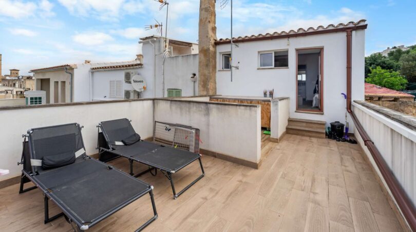 Terraza de azotea con baldosas de madera, dos tumbonas y pequeña construcción en Felanitx, Mallorca