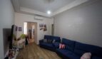 Sala de estar con sofá azul, pared de ladrillo blanco y aire acondicionado en unidad residencial alquilada en Felanitx