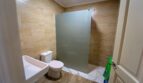 Baño con inodoro, lavabo y ducha con división de vidrio esmerilado, azulejos claros con aspecto de arenisca, casa multifamiliar Felanitx