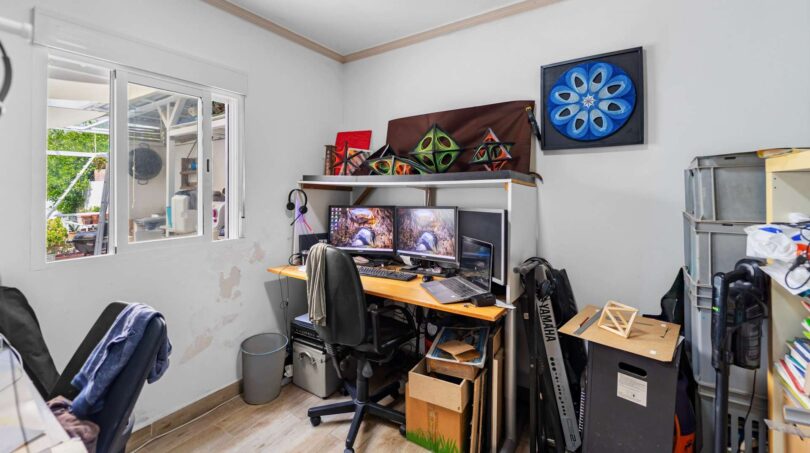 Despacho con configuración de doble monitor, teclado Yamaha, estanterías y piso de madera en casa unifamiliar Felanitx