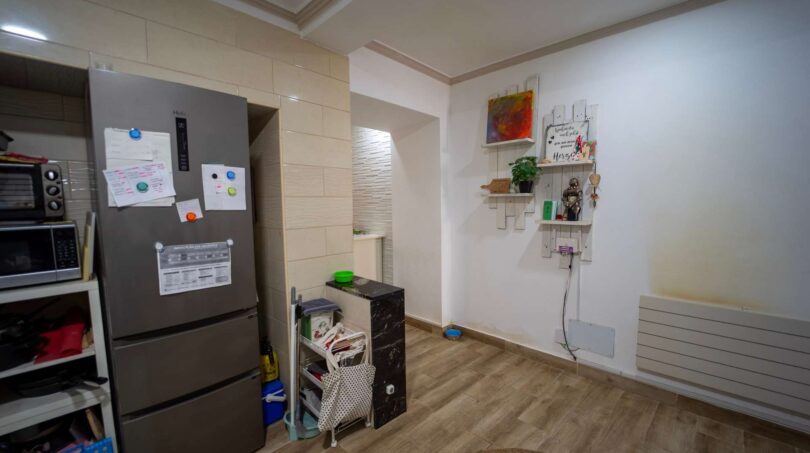 Cocina con refrigerador, microondas y estantes de pared en casa unifamiliar alquilada en Felanitx.