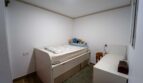 Pequeña habitación infantil con cama alta y almacenamiento en casa unifamiliar alquilada en Felanitx