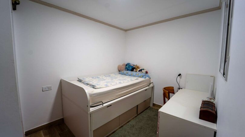 Pequeña habitación infantil con cama alta y almacenamiento en casa unifamiliar alquilada en Felanitx