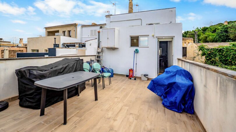 Terraza de azotea con tarimas de madera, muebles de jardín y vistas a los tejados de la ciudad de Felanitx