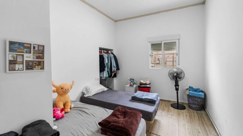 Pequeña habitación infantil con dos camas individuales, perchero y ventilador en casa unifamiliar alquilada en Felanitx.