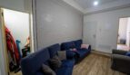 Sala de estar con sofá esquinero azul, suelo de madera y pared de piedra en casa unifamiliar alquilada en Felanitx