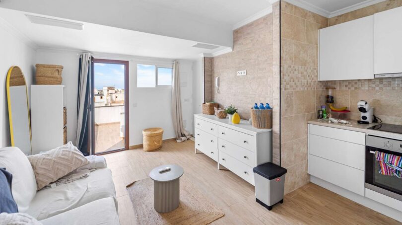 Luminoso comedor-sala con cocina abierta, suelo de madera y acceso a balcón en unidad alquilada, Felanitx